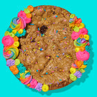 Gourmet chocolate chip cookie cake decorated with colorful frosting, sprinkles, and a turquoise background.