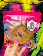 Chocolate chip specialty cookies delivery featuring a packaged cookie with vibrant graffiti-style packaging, held against a colorful street art background.