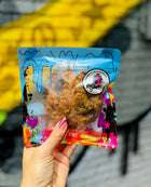 Specialty oatmeal and chocolate lactation cookie in vibrant Rebel Daughter Cookies packaging, held against a graffiti mural background.