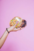 A woman's hand holding an array of 3 Rebel Daughter cookies against a pink background