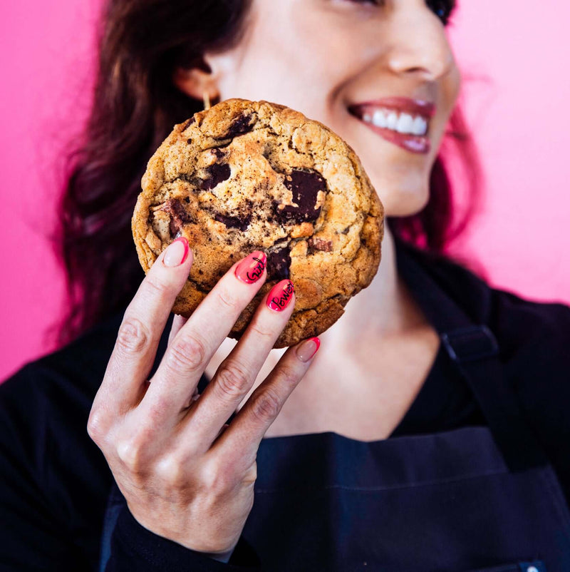 Rebel Daughter Cookies founder Anne F. Grossman holding a gourmet chocolate chunk "O(M)G" cookie