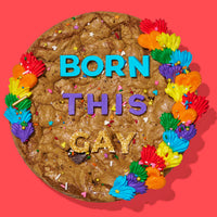 Rainbow-decorated gourmet cookie cake with colorful frosting, sprinkles, and bold lettering spelling out 