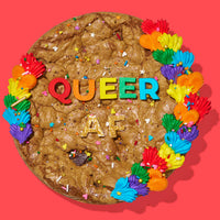 Decadent cookie cake decorated with rainbow frosting, sprinkles, and bold lettering that reads 