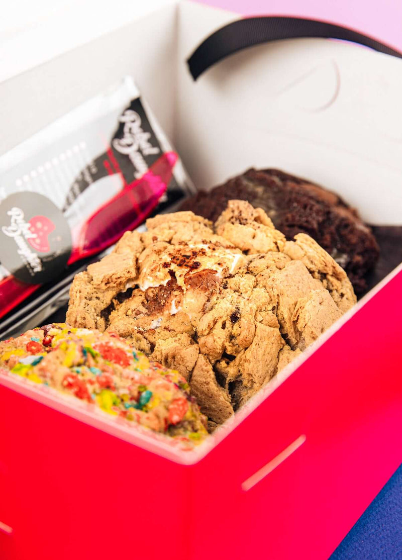 A pink Rebel Daughter Cookies delivery box with the lid open showing 3 cookies inside
