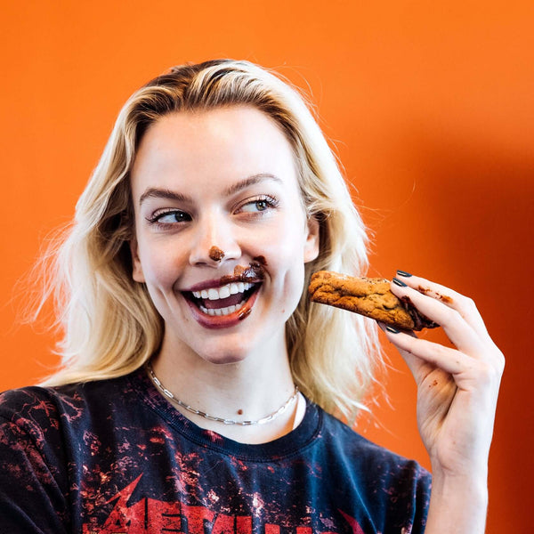 Model eating a gooey Rebel Daughter cookie with chocolate on her mouth