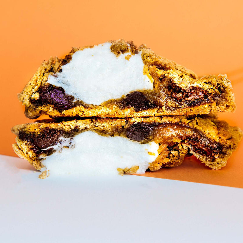 A Rebel Daughter Cookies gourmet chocolate chunk S'More, Please cookie cut in half and stacked against an orange background