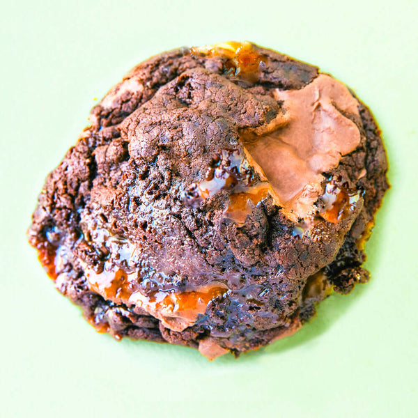 A Rebel Daughter gourmet chocolate chunk caramel brownie cookie against a light green background